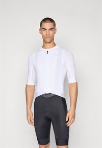 Hvit idrettsoverdel med korte ermer og glidelås foran, kombinert med svarte sykkelshorts med polstret sete.