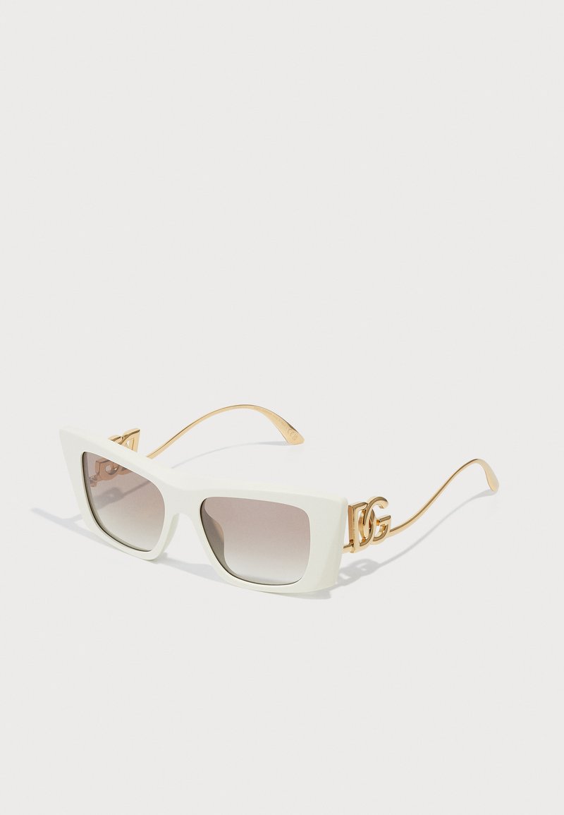 Baltas, pārmēra saulesbrilles ar leņķainiem rāmjiem, gradienta lēcām un zelta metāla akcentiem sānos. Rāmja strukturēta virsma.