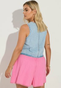 Jeans ärmlös topp i en ljusblå nyans, tillsammans med rosa veckade shorts med en scalloped nederkant.