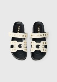 Λευκά δερμάτινα σανδάλια με δύο φαρδιές λουριά, διακοσμημένα με χρυσά καρφιά και σχέδιο κοπής σε σχήμα "G". Μαύρες λαστιχένιες σόλες και υφασμένη επιφάνεια στο πέλμα.