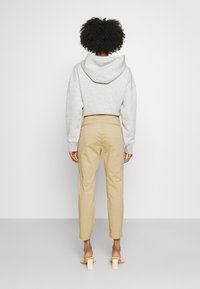 Grå hooded sweatshirt som kombineras med beige byxor. Sweatshirten har en avslappnad passform; byxorna har en smal design och sidofickor.