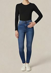 Černý top s dlouhým rukávem spojený s tmavě modrými džíny s vysokým pasem a úzkým střihem, které mají hladkou texturu a minimalistický design. Celý vzhled doplňují bílé tenisky.