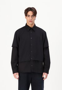 Cămașă neagră, cu buton, cu un design stratificat, având guler obișnuit, mâneci lungi și tiv drept. Fabricată dintr-un material neted.