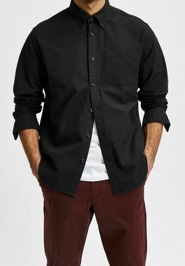 Zwarte button-up shirt met een kraag en een enkele zak, gemaakt van een gladde stof, gecombineerd met donkerrode broek. Mouwen opgerold.