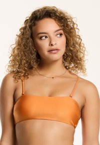 Top bikini bandeau arancione con sottili spalline regolabili, texture liscia e design minimalista. Nessun decoro o motivo.