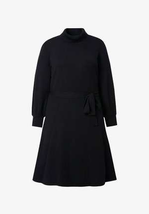 Musta neulemekko, jossa on korkea pyöreä kaula-aukko, pitkät pallohihojen ja vyötärölle solmittava nauha. Hame on leveä, luoden rennon siluetin.