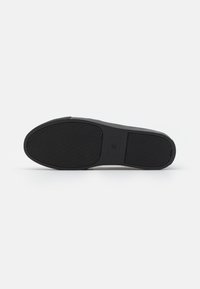 Black rubber shoe sole with a textured surface featuring horizontal grooves and an oval shape. Includes a flat edge and a logo imprint.
