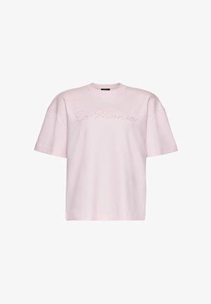 Jasnoróżowa, luźna koszulka z krótkim rękawem z haftowanym napisem "La Mania" w kursywie na wysokości klatki piersiowej.