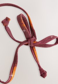 Blød slips lavet af skinnende stof med en dyb bordeauxfarve og orange accenter, med en knyttet detalje og glat tekstur.