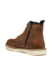 Botas de tobillo de cuero marrón con cremallera lateral, puntera redonda, cordones amarillos y suela de goma crema con textura.