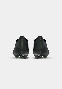 Bottes de football noires au design épuré, avec une tige texturée et des accents verts. Elles présentent un talon angulé et des crampons multidirectionnels pour une meilleure traction.