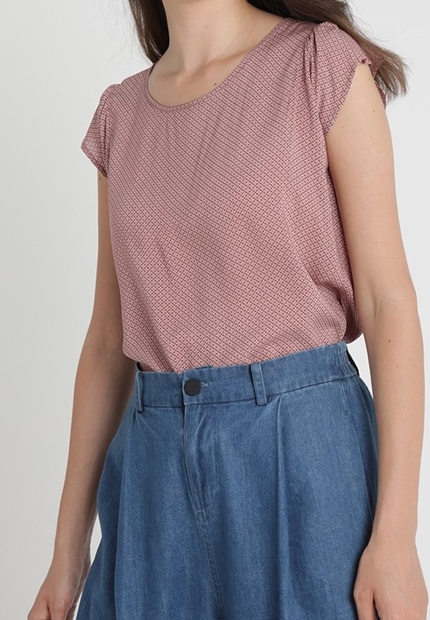 Blusa rosa con fantasia a maniche corte abbinata a una gonna di jeans a vita alta con chiusura a bottoni e design plissettato.