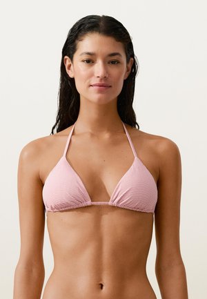 Nő nedves hajjal, rózsaszín és fehér csíkos háromszög alakú bikini felsőben, egyszerű, világos háttér előtt.