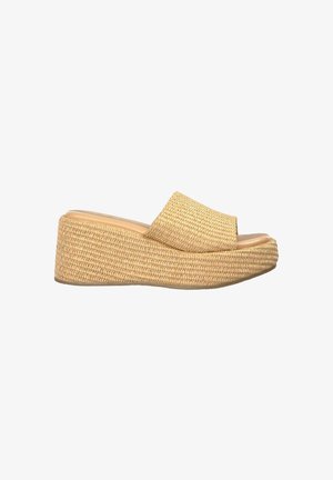 Mules plates tissés beiges avec une large bride, présentant une surface texturée et un bout rond, reposant sur une base solide.