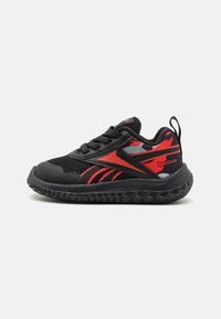 Zapatillas negras y rojas con una parte superior de malla transpirable, entresuela negra texturizada y suela de goma con un patrón de zigzag. Logotipo de Reebok visible.