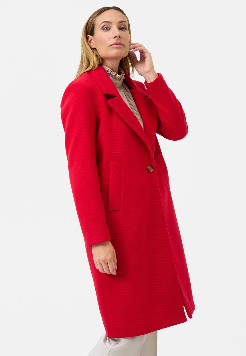 Rode jas met een notch-kraag, enkele knoopsluiting, twee zijzakken en een gestructureerde stof. Halflang ontwerp met lange mouwen.