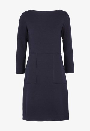 Laivastonsininen polvipituinen mekko, jossa on puolipitkät hihat, istuva vyötärö ja kaksi etuosassa olevaa suorakaiteen muotoista läppätaskua.