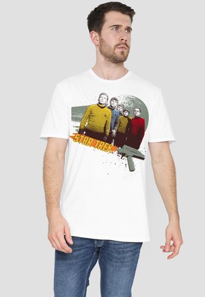 White cotton T-shirt featuring a graphic of five characters in colorful uniforms with "Star Trek" text and a stylized gun illustration.