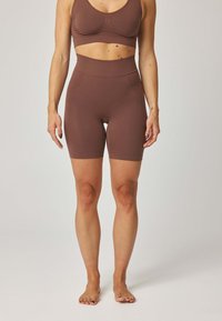 Brązowy komplet sportowy składający się z biustonosza i szortów z wysokim stanem, wykonany z elastycznej tkaniny o gładkiej fakturze. Posiada dopasowany krój i subtelne szwy.