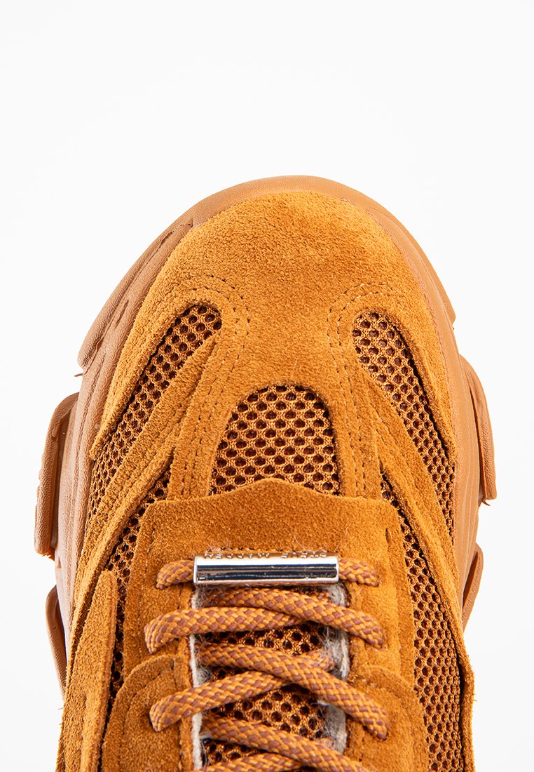 Sneaker arancione in suede con pannelli in rete, una punta ampia, elementi di design sovrapposti e una placca logo argentata sulla linguetta.