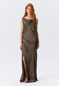 Maxi dress in olive green satin, featuring a cowl neckline, asymmetrical draping, and a thigh-high side slit. Smooth texture throughout.