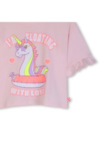 Ροζ κοντομάνικο πουκάμισο με κυματιστές άκρες, που απεικονίζει ένα ουράνιο τόξο με μονόκερο που φοράει γυαλιά ηλίου σε σχήμα αστεριού, να επιπλέει σε ένα σωσίβιο με καρδιές.