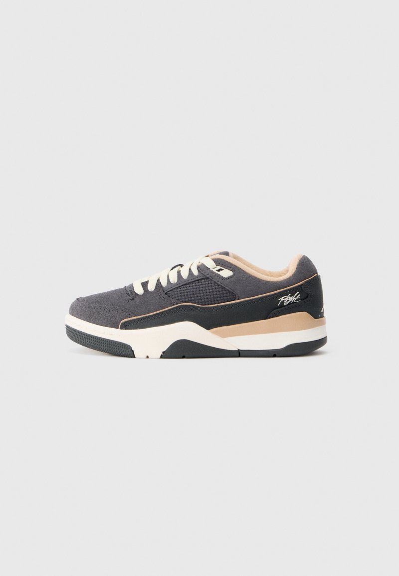 Zapatillas de estilo bajo en gris oscuro y beige con cordones blancos, acentos de suela negra y paneles de tela texturizada sobre un fondo liso.