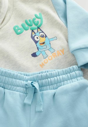 Ensemble deux pièces bleu comprenant un haut gris clair avec un imprimé coloré "Bluey" et un pantalon bleu clair avec une taille élastique.