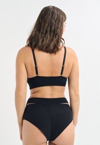 Black bikini set with a textured high-waisted bottom and a bralette-style top featuring adjustable straps and minimal hardware details.