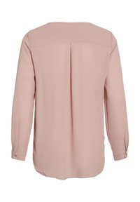 Blouse rose clair à manches longues avec couture d’empiècement au dos et pli creux inversé central, poignets boutonnés et ourlet arrondi.