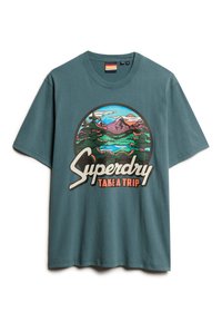 Camiseta de algodón en color azul verdoso con un gráfico circular que incluye montañas, árboles y agua, y el texto "Superdry TAKE A TRIP" en blanco y naranja.
