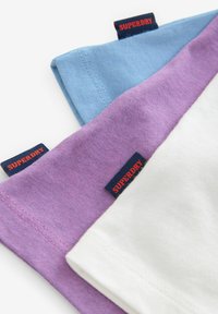 Tre stofkravekanter i lyseblå, lavendel og hvid, med broderede "SUPERDRY"-mærker i marineblå med rød tekst.