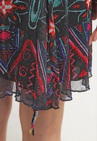 Abito nero trasparente con motivi floreali e astratti vibranti in rosso, blu e verde. Presenta un cordoncino all'orlo per una lunghezza regolabile.