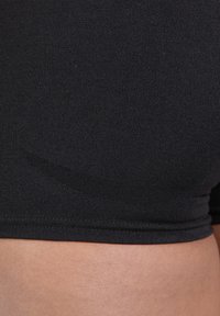 Pantaloni sportivi neri realizzati in tessuto liscio con una fascia strutturata, caratterizzati da un design aderente e senza cuciture o loghi visibili.