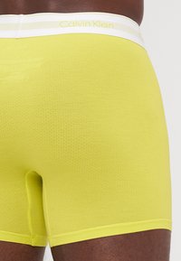 Gelbe Calvin Klein Boxer Shorts aus einem strukturierten Stoff mit einem weichen Bund, bedrucktem Logo und einer figurschmeichelnden Passform.