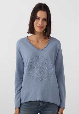 Helles blaues Langarmoberteil mit V-Ausschnitt, ausgefransten Rändern und geprägtem kreisförmigen Textdesign, das "POSITIVE LIFE" und "POSITIVE MIND CLUB" besagt.