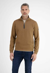 Bruine zip-up trui met een gestructureerd oppervlak, geribde manchetten en zoom. Heeft een contrasterende rits en een logo-patch op de linker mouw.