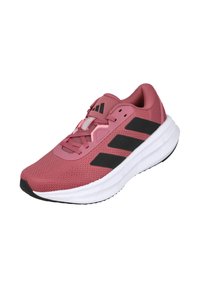 Zapatilla deportiva rosa con parte superior de malla texturizada, rayas negras y una mediasuela blanca. Presenta cordones y un collar acolchado para mayor comodidad.