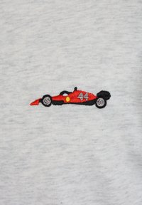 Κόκκινο αγωνιστικό αυτοκίνητο Formula 1 με τον αριθμό 44 κεντημένο σε ανοιχτό γκρι ύφασμα, που δείχνει λεπτομερή ραφή του αυτοκινήτου και των τροχών.