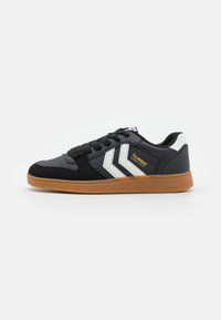Black athletic sneakers with suede and synthetic material, featuring white stripes and a gum rubber sole. Branding visible on the side.