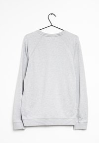 Sweat-shirt gris clair en mélange de coton, doté d'un col rond, de manches raglan, de poignets et d'un ourlet côtelés, avec une texture lisse. Suspendu à un crochet noir.