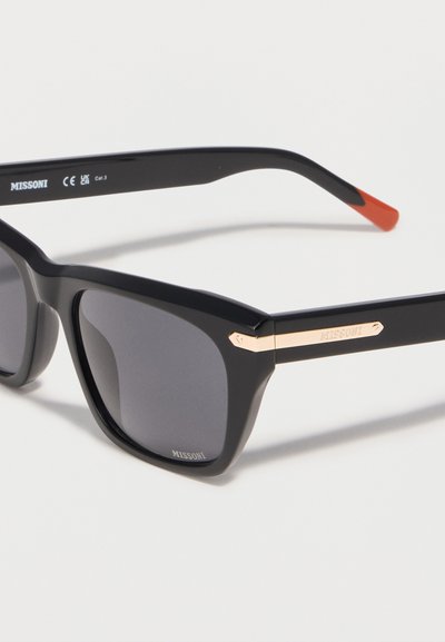 Μαύρα ορθογώνια γυαλιά ηλίου με σκουρόχρωμους φακούς, χρυσή πλακέτα με το λογότυπο στα κλαδιά και κόκκινα-πορτοκαλί άκρα στα βραχίονες.