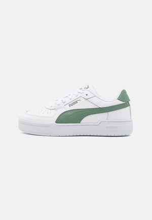 Weißer Puma Low-Top Sneaker mit grünem Seitenstreifen, perforierter Zehenpartie und weißer Sohle, seitlich auf schlichtem Hintergrund gezeigt.