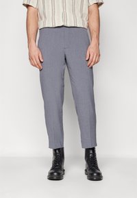 Grijze op maat gemaakte broek met een gladde textuur, uitgevoerd in een regular fit en met een cropped lengte. Gecombineerd met zwarte veterlaarzen.