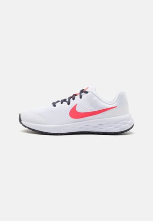 Zapatilla deportiva blanca con parte superior de malla, logo de swoosh rosa, cordones azul marino y suela exterior de goma negra texturizada. Diseñada para la comodidad y el soporte.