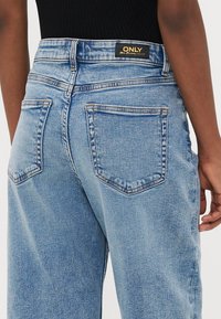 Ανοιχτό μπλε τζιν παντελόνι με ψηλή μέση, με μαύρη ετικέτα "ONLY", δύο πίσω τσέπες και ελαφρώς φθαρμένη υφή.