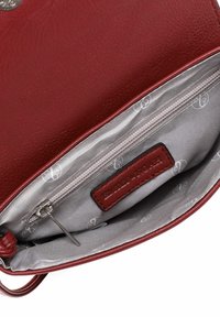 Red leather handbag interior with a zippered pocket. Lining features a light gray fabric with a repeating logo pattern.