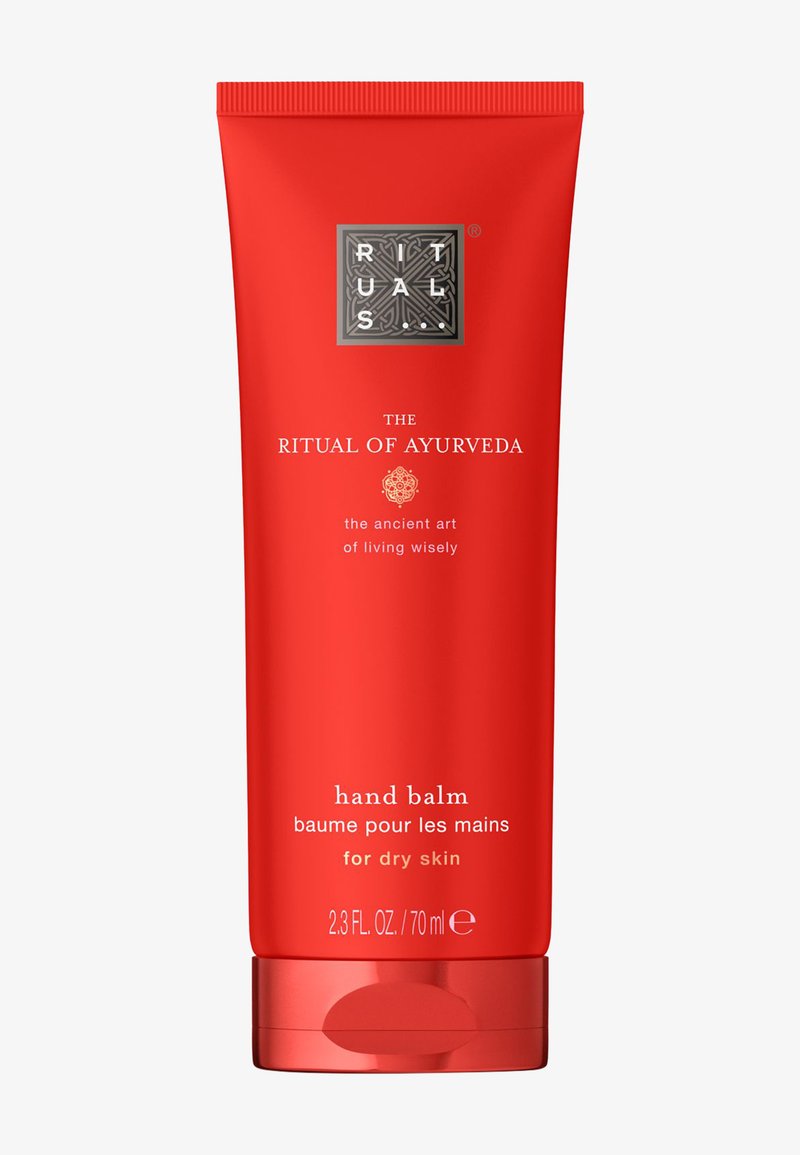 Rød tube med Ritual of Ayurveda håndbalm for tørr hud, 70 ml, med merke-logo og produktnavn foran.
