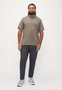 Pilkas medvilninis trumpomis rankovėmis marškinėlis, derinamas su tamsiai pilkomis kelnėmis. Avalynė turi tekstūruotą viršutinę dalį ir šviesios spalvos pado.