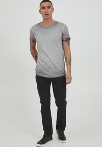 Grå gradient t-skjorte med rund hals og korte ermer, sammen med svarte jeans og svarte joggesko. Glatt stoff, avslappet passform.